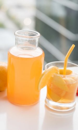 peach-orange-juice-bottle-glass-juice-white-desk_23-2148103646